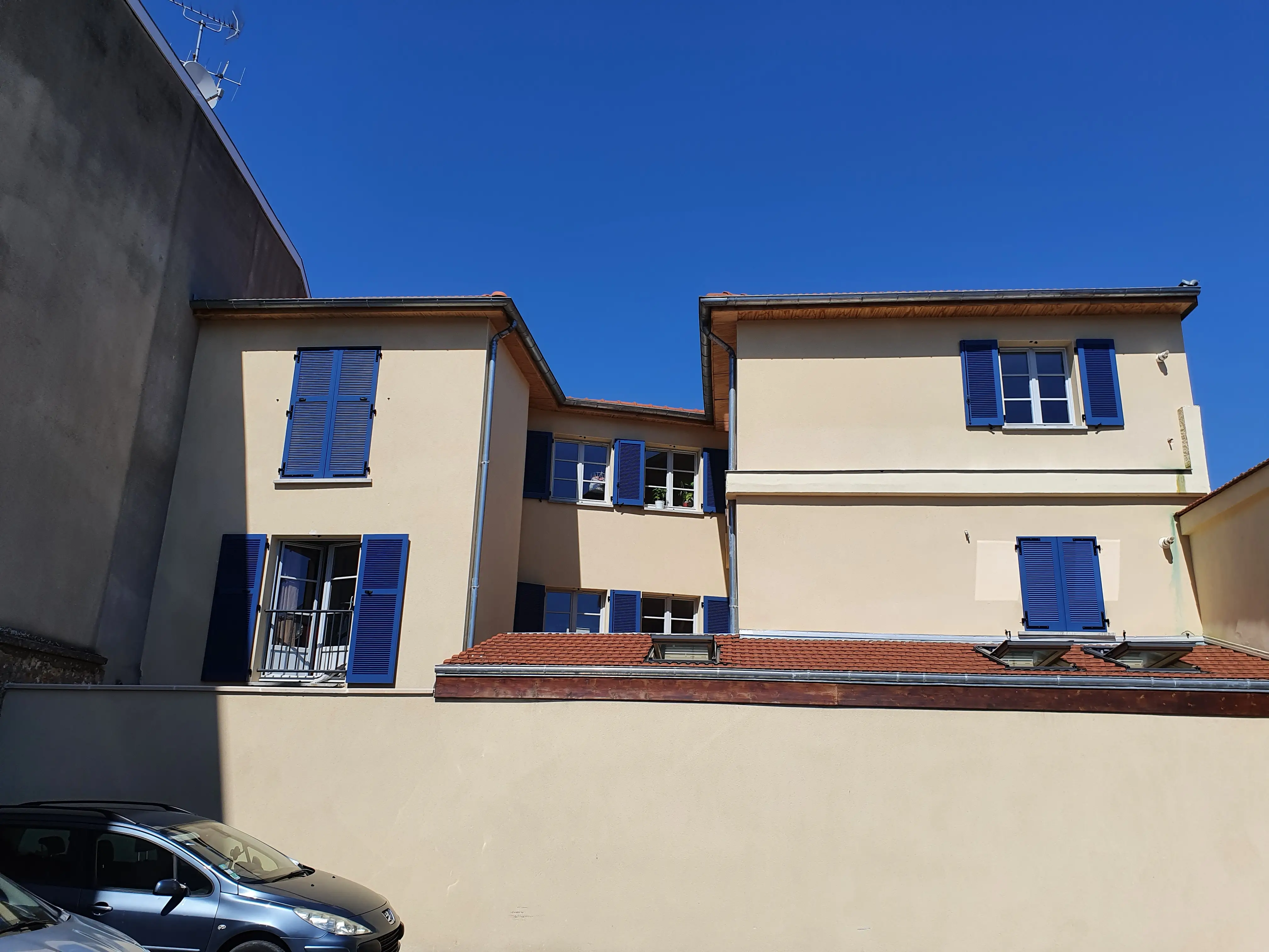 Volets battants aluminium bleus sur façade beige